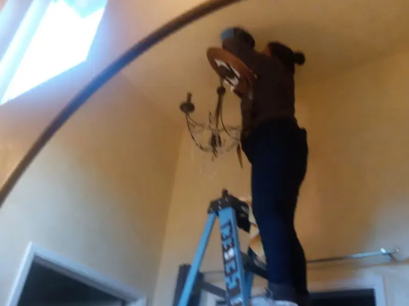 Electrician installing a chandelier in a Huntley residence